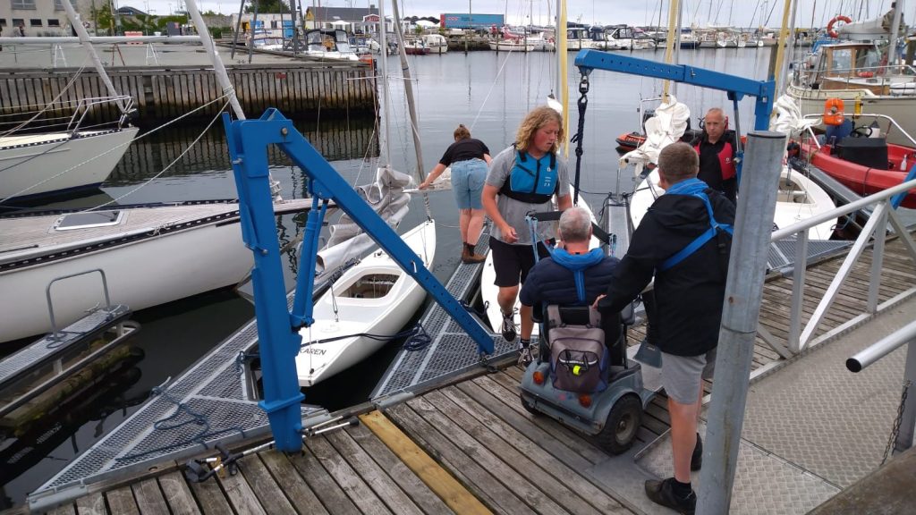 Über eine kleine Rampe gelangt ein Rollstuhlfahrer problemlos auf einen Bootssteg.
